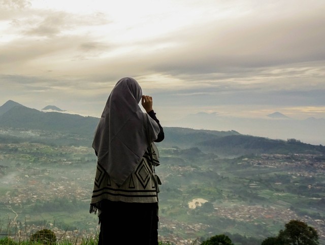 Fatimah Az Zahra dalam pakaian tradisional dan berdiri di tengah kerumunan orang
