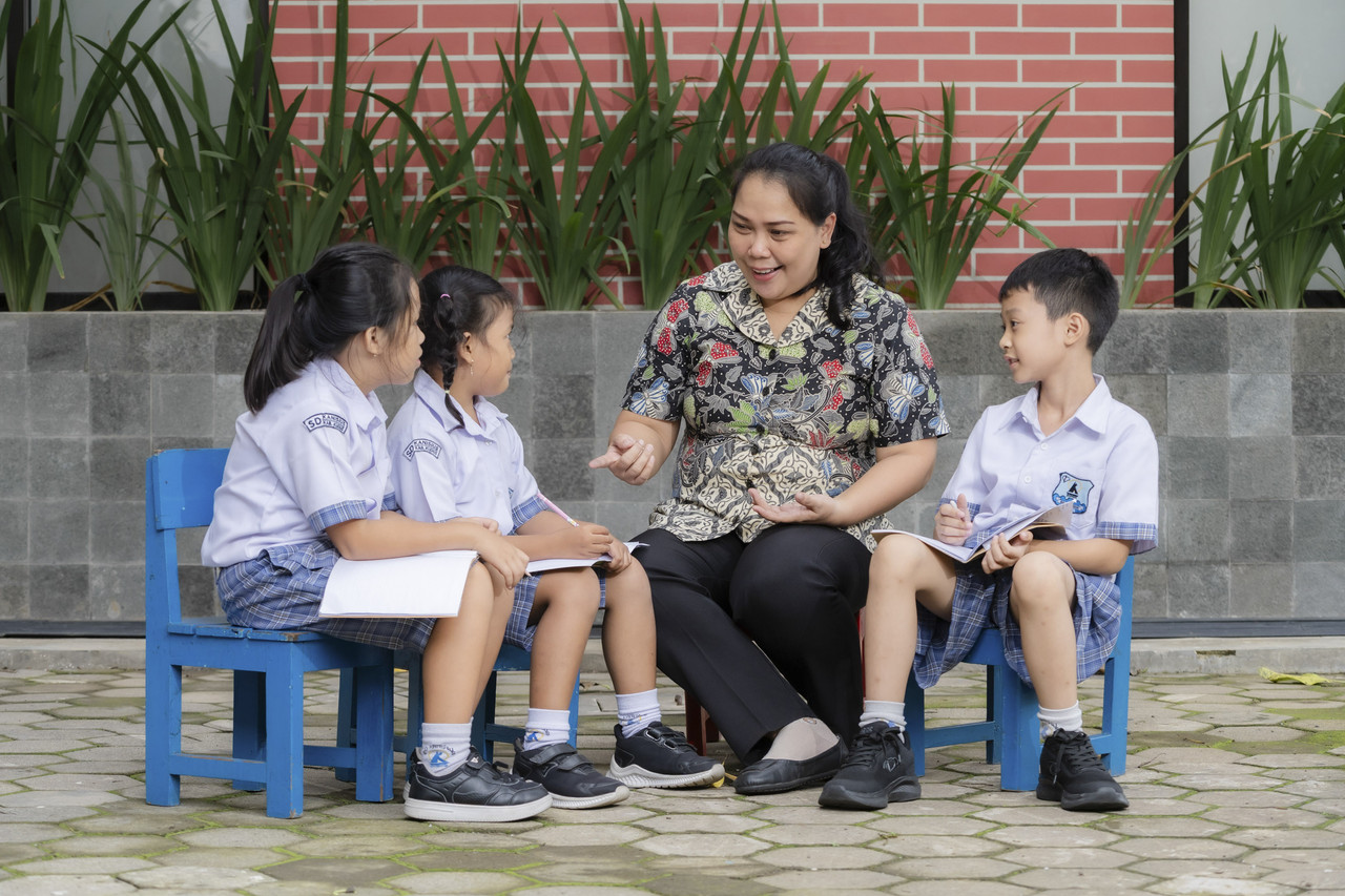 Ilustrasi anak berdiskusi dengan guru di sekolah.