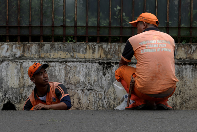 Pekerja Petugas Pelayanan Prasarana dan Sarana Umum (PPSU) turun ke dalam got. (Foto: Fanny Kusumawardhani/kumparan)