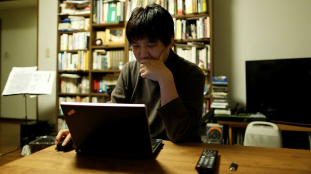 Pekerja Jepang sedang mengecek pasar saham. (Foto: Issei Kato/Reuters)