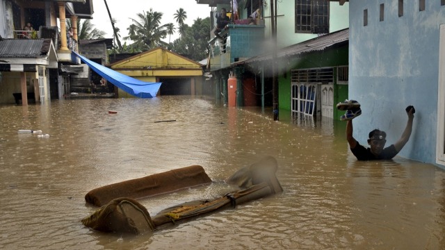 Warga menembus banjir di Kampung Mahawu, Manado. (Foto: Adwit Pramono/Antara)