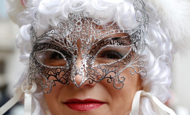 Peserta Karnaval dengan topeng perak. (Foto: Reuters/Tony Gentile)