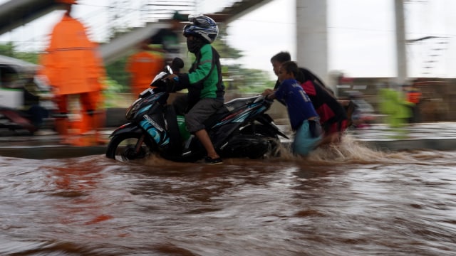 Pengendara sepeda motor melintasi banjir. Foto: Aditia Noviansyah/kumparan