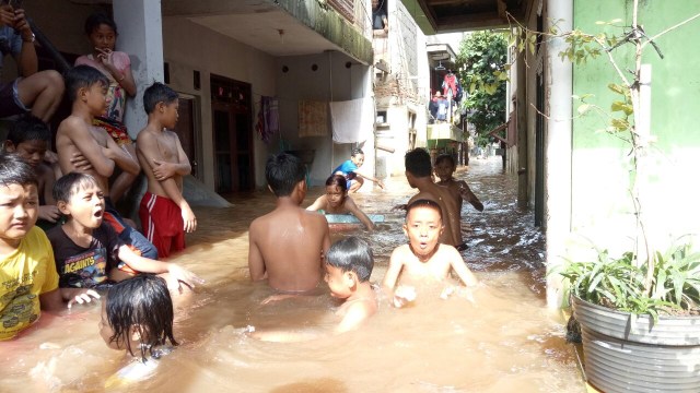 Anak-anak berenang di darah banjir. (Foto: Amanaturrosyidah/kumparan)