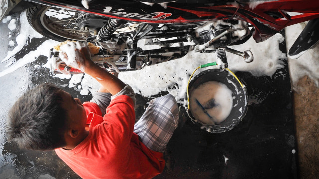 Ridwan tengah mencuci motor. (Foto: Kevin Kurnianto/kumparan)