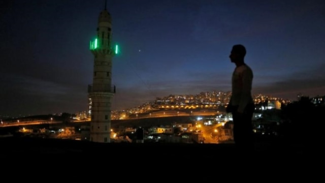 Seorang laki-laki berdiri dekat masjid. (Foto: Reuters/Ammar Awad)