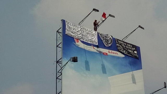 Seorang pria protes dan memanjat di atas baliho (Foto: Marcia Audita/kumparan)