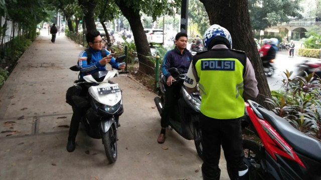 Tilang pengendara motor yang melintasi trotoar (Foto: Twitter @TMCPoldaMetro)