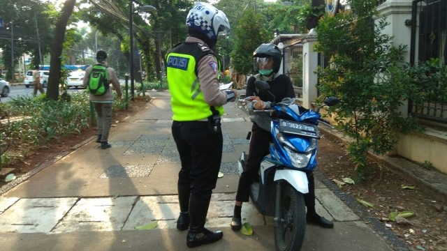 Tilang pengendara motor yang melintasi trotoar (Foto: Twitter @TMCPoldaMetro)