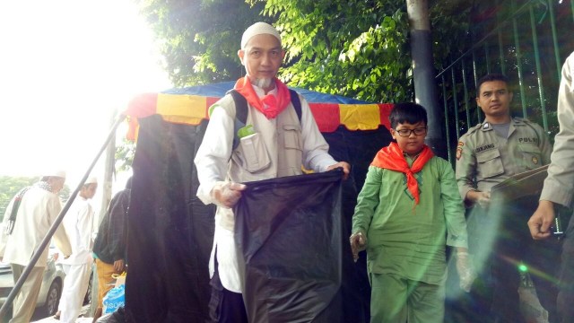 Ika dan anaknya bersihkan sampah aksi reuni 212 (Foto: Kevin Kurnianto/kumparan)