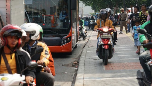 Pengguna sepeda motor melintasi trotoar (Foto: Jamal Ramadhan/kumparan)