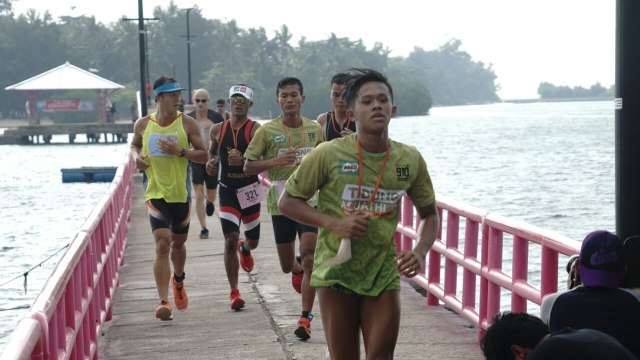 Peserta Tidung Aquathlon melewati Jembatan Cinta. (Foto: Helmi Afandi/kumparan)