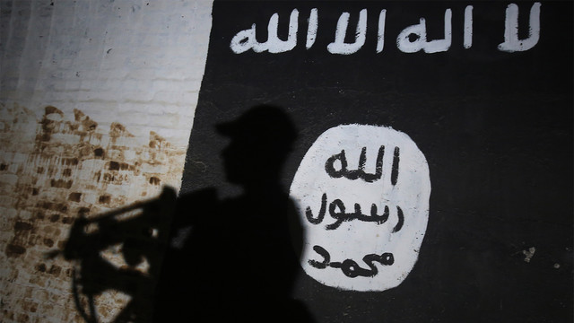 Seorang tentara Irak berjalan lewati mural ISIS. (Foto: AFP PHOTO / Ahmad Al-Rubaye)