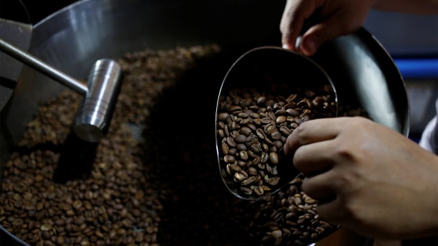 Seorang pekerja memanggang biji kopi lokal dengan roaster kayu bakar tradisional di Kopi Aroma di Bandung. (Foto: REUTERS / Willy Kurniawan)
