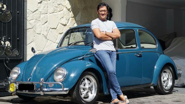 Andre Taulany berpose di depan mobil klasik koleksinya. (Foto: Instagram @andreastaulany)