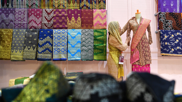 Pramuniaga menata busana yang dipamerkan dalam Karya Kreatif Indonesia (KKI) 2018 di JCC, Senayan, Jakarta, Jumat (20/7). (Foto: ANTARA FOTO/Sigid Kurniawan)