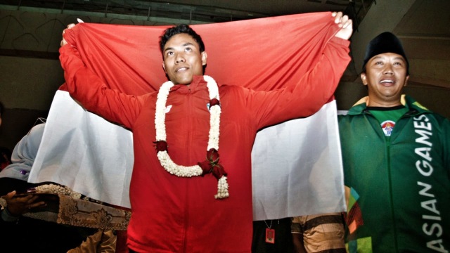 Juara dunia atletik nomor Lari 100 meter U-20 Lalu Muhammad Zohri (kiri) mengangkat bendera merah putih saat tiba di Bandara Internasional Soekarno Hatta, Tangerang, Selasa (17/7). Foto: AFP PHOTO / Demy Sanjaya