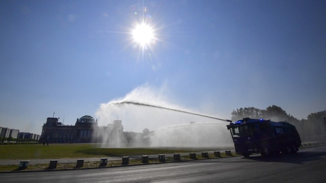 Polisi Berlin menggunakan meriam air menyirami taman publik di depan gedung Reichstags, Bundestag, di Berlin Jumat (27/7).
 (Foto:  SCHWARZ / AFP/Tobias Schwarz)
