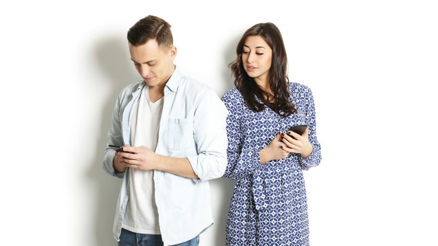 Perempuan mengintip handphone pasangannya. (Foto: Thinkstock)
