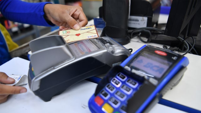 Pramuniaga mengisi saldo uang elektronik konsumen di sebuah toko waralaba, Jakarta, Kamis (2/8). Foto: ANTARA FOTO/Sigid Kurniawan