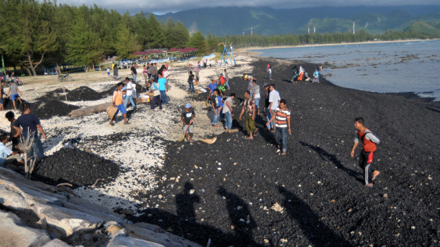 Warga bersama nelayan membersihkan tumpahan batu bara dari kapal tongkang yang kandas di perairan pantai Ujung Kareng, Lhoknga, Aceh Besar, Aceh, Jumat (3/8). Foto: Antara/Ampelsa