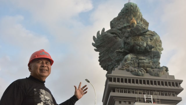 Pemrakarsa Patung Garuda Wisnu Kencana (GWK) Nyoman Nuarta berfoto dengan latar belakang Patung GWK di Ungasan, Badung, Bali, Selasa (31/7). (Foto: Antara/Fikri Yusuf)