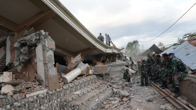 Petugas berusaha mengevakuasi korban yang tertimpa bangunan mesjid di Karang Pangsor, Kecamatan Pemenang, Lombok Utara, Selasa (7/8). (Foto: Jamal Ramadhan/kumparan)