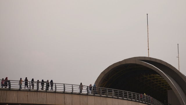Penumpang Light Rail Transit (LRT) Palembang berjalan di walk way menuju stasiun Jakabaring Palembang, Sumatera Selatan, Minggu (12/8/2018), karena LRT mogok.. (Foto: Antara/Mushaful Imam)