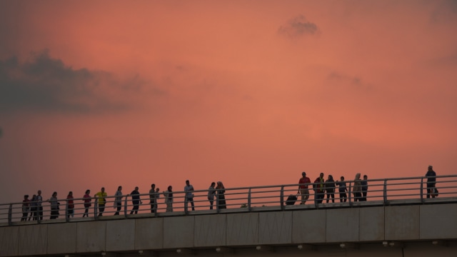 Penumpang Light Rail Transit (LRT) Palembang berjalan di walk way menuju stasiun Jakabaring Palembang, Sumatera Selatan, Minggu (12/8/2018), karena LRT mogok. (Foto: Antara/Mushaful Imam)