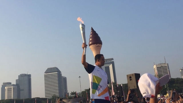 Gubernur Anies Baswedan membawa obor Asian Games 2018 di Monas, Sabtu (18/82018). (Foto: Moh Fajri/kumparan)