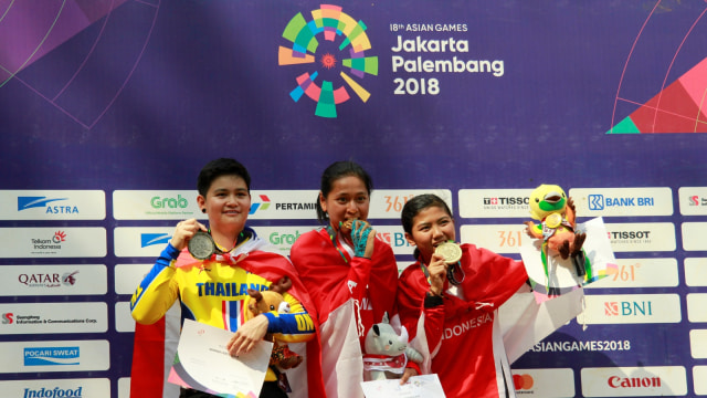 Atlet Sepeda Gunung Indonesia peraih medali emas Tiara Andini Prastika (tengah) bersama pebalap Thailand, Vipavee Deekaballes yang meraih perak (kiri) dan pebalap Indonesia Nining Porwoningsih meraih perunggu (kanan) usai Final Run Women Elite Downhill pada Asian Games ke-18 Tahun 2018. (Foto: ANTARA FOTO/NASGOC/Aji Wisnu Novianto)