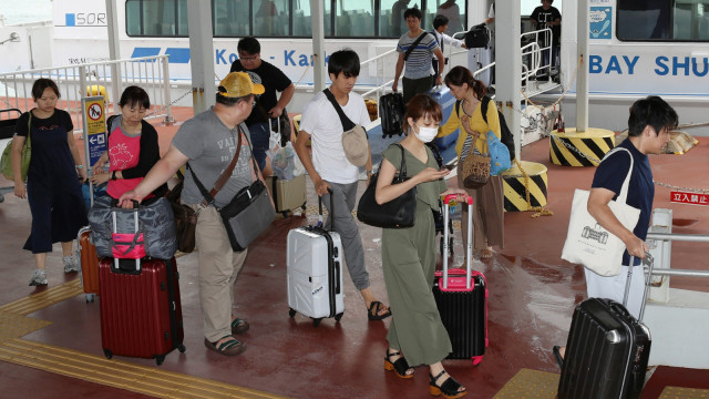 Penumpang yang terjebak di Bandara Internasional Kansai karena topan Jebi tiba di pelabuhan Kobe dengan kapal. (Foto: JIJI PRESS/AFP)
