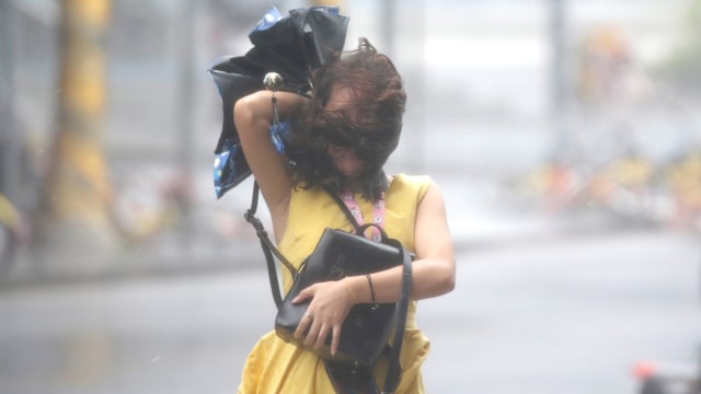 Seorang perempuan berjalan di tengah hantaman Topan Mangkhut yang menerpa Shenzhen, Cina, Minggu (16/9/2018). (Foto: REUTERS/Jason Lee)