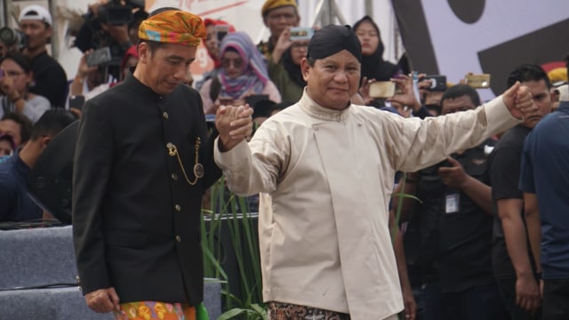 Jokowi (kiri) dan Prabowo (kanan) bergandengan usai menandatangani deklarasi kampanye damai Pemilu 2019 di Monas, Jakarta, Minggu (23/9/2018). (Foto: Fanny Kusumawardhani/kumparan)