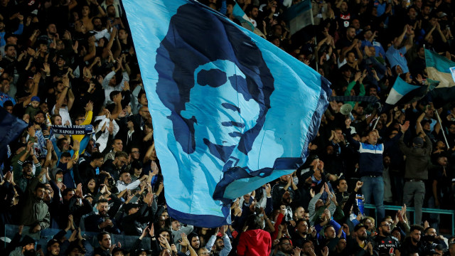 Suporter Napoli mengibarkan bendera bergambar wajah Maradona di laga melawan Parma. (Foto: REUTERS/Ciro De Luca)