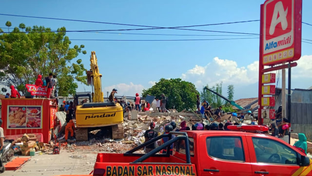 Warga mengambil makanan dari 'minimarket' yang ambruk di Palu, Sulawesi Tengah, Minggu (30/9). Warga terpaksa mengambil karena mereka juga membutuhkan makanan dan air bersih. (Foto: ANTARA FOTO/Rolex Malaha)