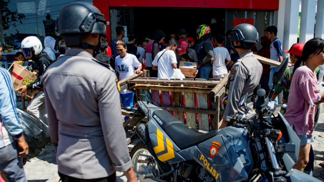 Polisi melihat warga yang menjarah toko swalayan di Palu, di Sulawesi Tengah, pada 30 September 2018. (Foto: AFP/ BAY ISMOYO)