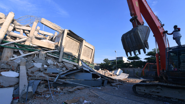 Petugas mencari korban yang tertimbun di bangunan hotel Roa Roa yang runtuh di Palu.  (Foto: APF/ Adek Berry)
