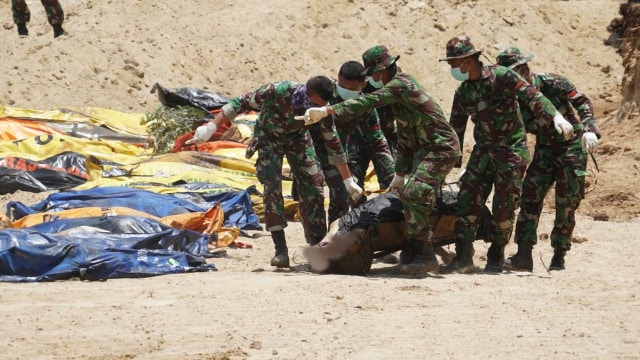 TNI membantu prosesi Pemakaman masal korban akibat bencana gempa dan tsunami Palu. (Foto: Jamal Ramadhan/kumparan)