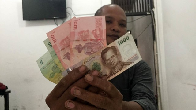 Seseorang sedang menunjukkan mata uang Bath. (Foto: Zuhri Noviandi/kumparan)