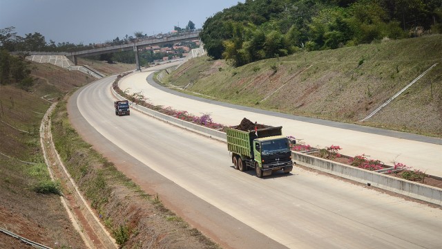 Pekerja membawa material proyek jalan tol Cileunyi-Sumedang-Dawuan (Cisumdawu) dengan truk di Pamulihan, Kabupaten Sumedang, Jawa Barat. (Foto: ANTARA FOTO/Raisan Al Farisi)