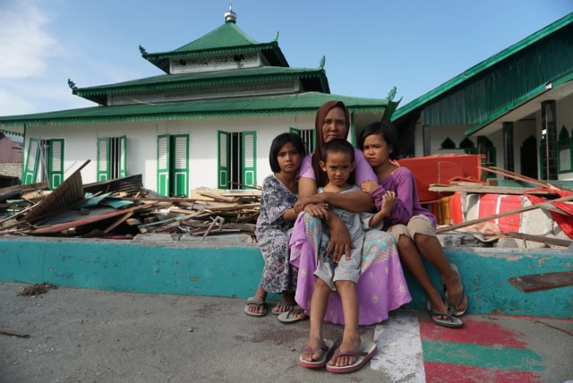 Mas'ulin berfoto bersama anaknya Putri Ramadhani (tengah), Nur Nissa (kanan) dan Ainun Naziah di depan Masjid Al-Amiin. (Foto: Jamal Ramadhan/kumparan)