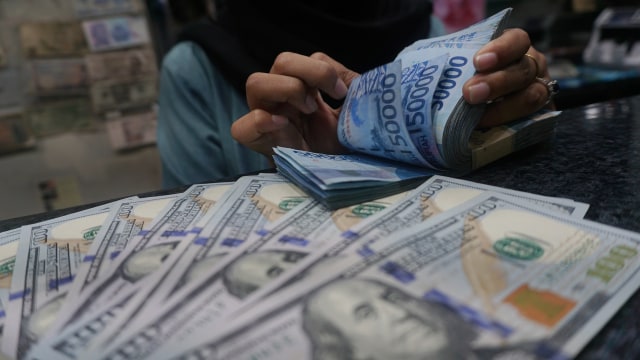 Petugas memperlihatkan pecahan uang dolar dan rupiah di salah satu tempat penukaran mata uang asing/money changer di Jakarta. Foto: Fanny Kusumawardhani/kumparan