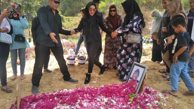 Roro Fitria peluk makam Ibunda di TPU Pemerintah Kabupaten (Pemkab) Sleman di Beran, Margodadi, Seyegan, Sleman, Selasa (16/10/2018). (Foto: Arfiansyah Panji Purnandaru/kumparan)