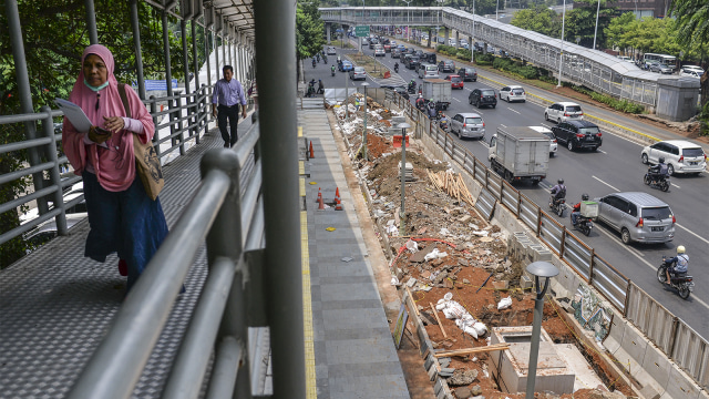 Warga berjalan di samping proyek penataan ulang trotoar Jalan Jenderal Sudirman, Jakarta. (Foto: ANTARA FOTO/Aprillio Akbar)
