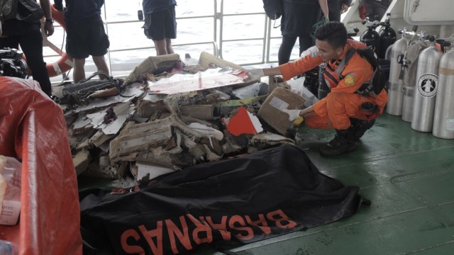Sejumlah anggota Basarnas membawa puing-puing pecahan pesawat Lion Air JT-610 dan jenazah korban ke dalam kapal induk Basarnas di perairan Tanjung Pakis, Karawang, Selasa (30/10). (Foto: Aditia Noviansyah/kumparan)