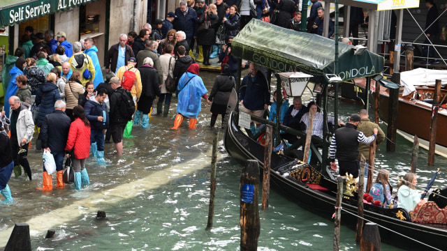 Orang-orang berjalan di atas jembatan gantung di St Mark Square yang terkena banjir di Venesia. (Foto: AFP/Miguel MEDINA)