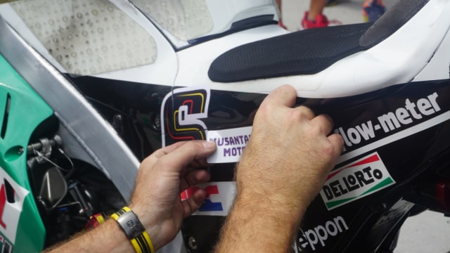 Menempelkan stiker bengkel Indonesia di motor LCR Honda. Foto: Anju Christian/kumparan
