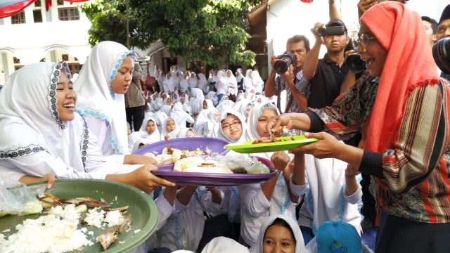 Menteri Kelautan dan Perikanan Susi Pudjiastuti membagikan ikan kepada santriwati di Pondok Pesantren Darussalam Banyuwangi, Sabtu (3/11/2018). (Foto: Muhammad Miradi/kumparan)
