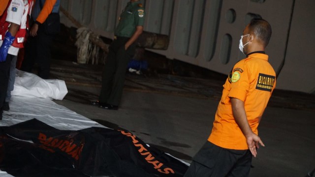 Petugas tim SAR gabungan memindahkan potongan tubuh ke kantong jenazah yang baru. (Foto: Jamal Ramadhan/kumparan)